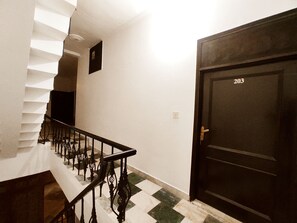 Una escala amb barana que porta a una porta amb el número 203.