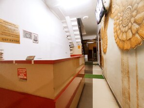 A hotel reception area with a counter, a sign indicating a 24-hour AC room, and a wall with a floral design. - Premium Rooms For Corporates, Couples, Families, Students And Travelers (Ludhiana)