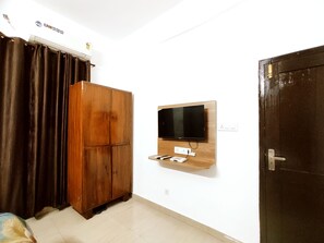 A room with a wooden wardrobe, a mounted television, and a door.