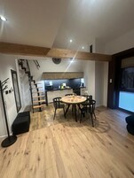 A modern kitchen with a dining area, wooden beams, and a staircase.