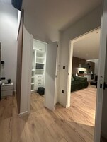 A modern apartment with a wooden floor, a green sofa, a kitchen area, and a white storage unit.