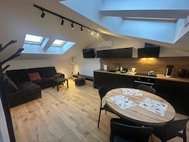 A modern loft apartment with a dining area, kitchen, and living space.