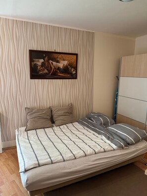 Ein Bett mit gestreifter Bettwäsche, ein Bild an der Wand und ein Holzboden.