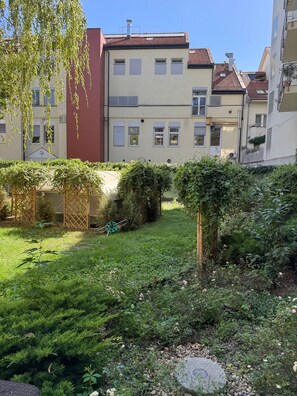 Ein Wohnhof mit Garten, einem Holzzaun und einem Gebäude mit mehreren Fenstern und Balkonen.