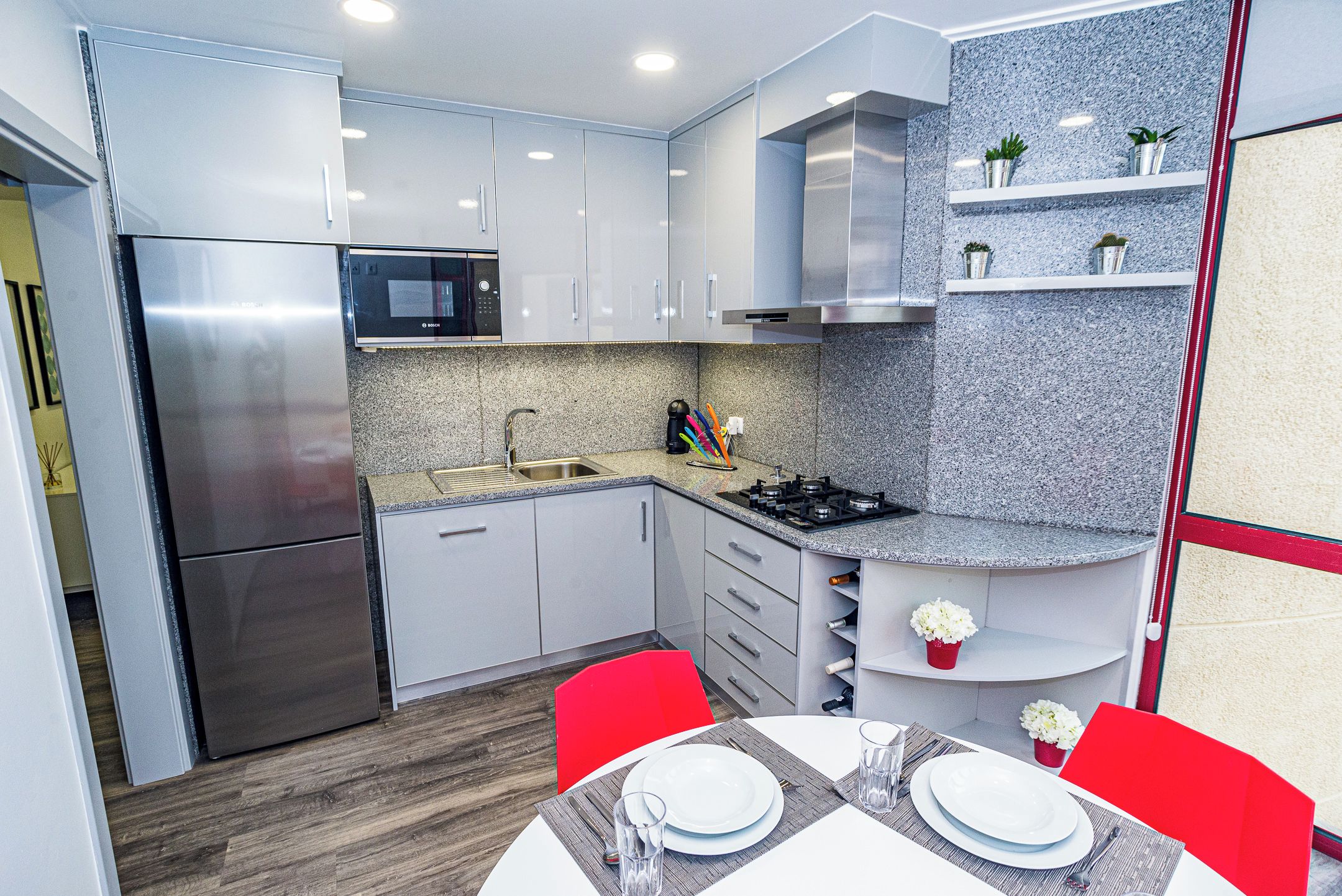 Una cocina compacta con electrodomésticos de acero inoxidable, microondas y cocina a gas.