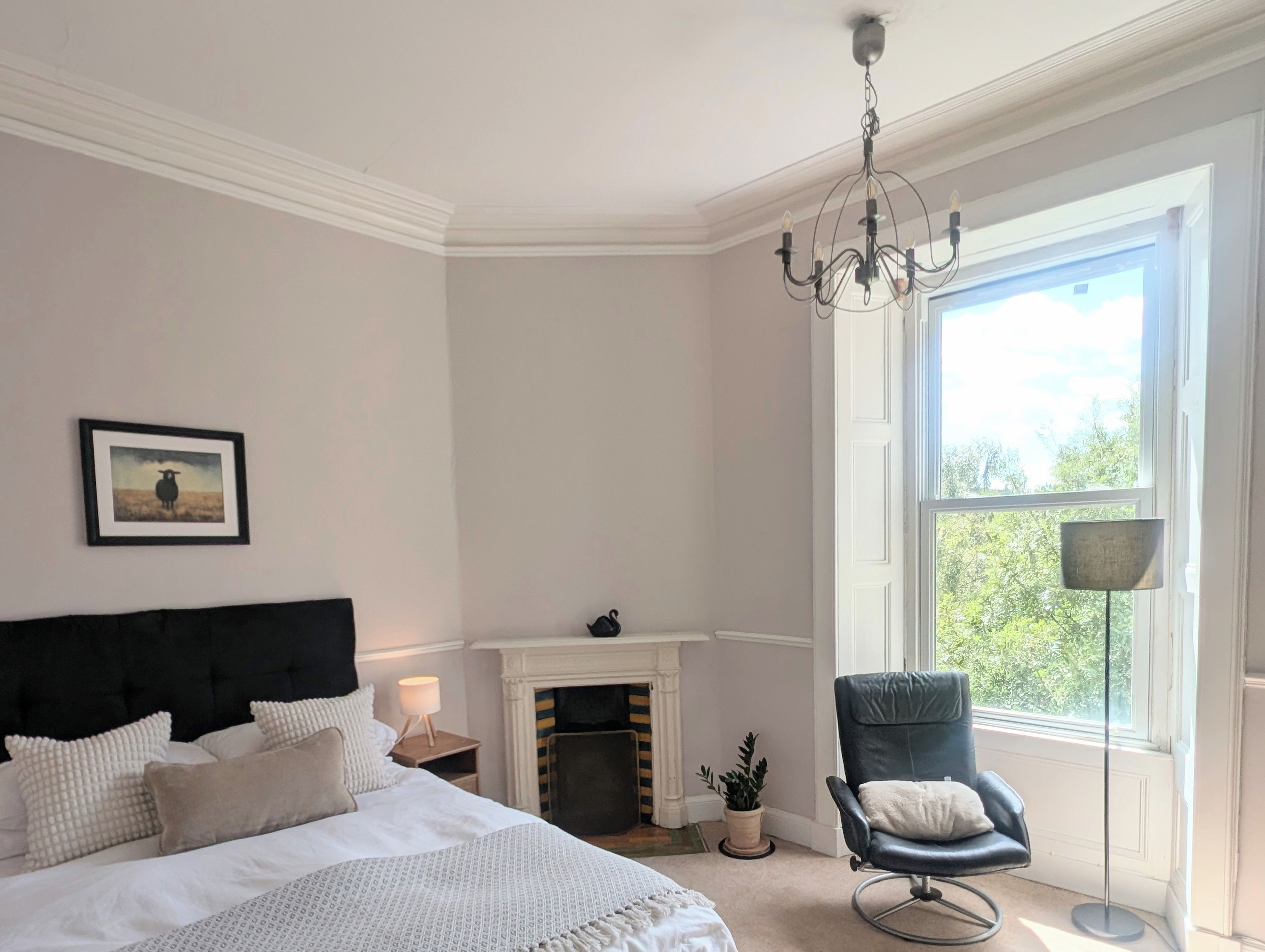 Une chambre à coucher avec un lit, une cheminée, un fauteuil et une fenêtre donnant sur un beau paysage.