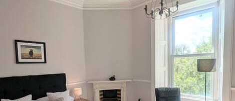 A bedroom with a bed, a fireplace, a chair, and a window with a view.