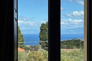 A view through a window with a clear sky, distant trees, and a body of water. - Capovillas - Silent Country House (Gasponi)