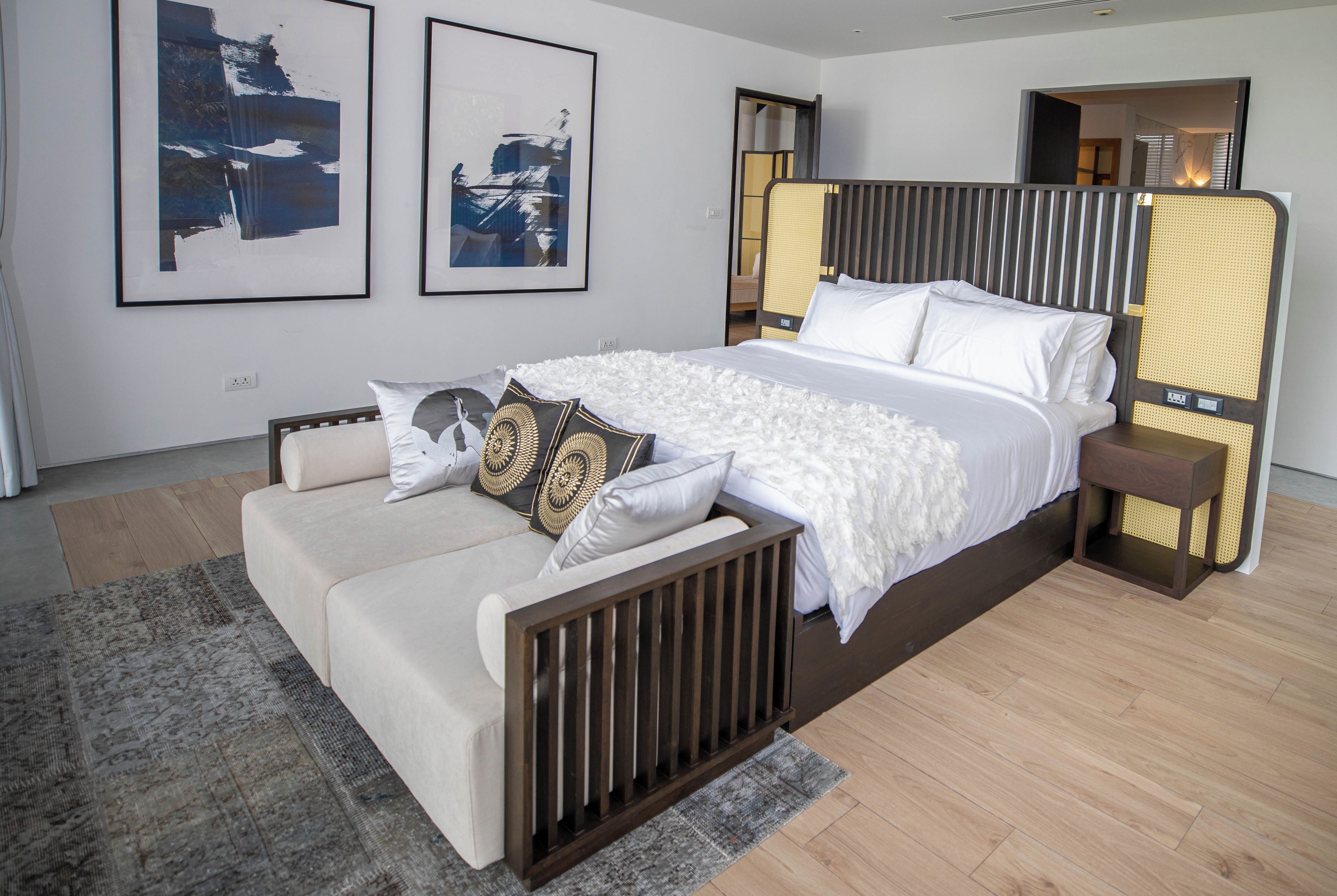 Una camera da letto moderna con un letto grande, un comodino, una poltrona e due opere d'arte appese al muro.