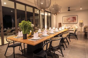 Comedor con una larga mesa de madera dispuesta para una comida, rodeado de sillas.