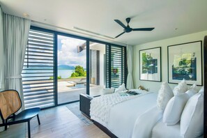 Un dormitorio con una cama grande, una silla y vistas a un cuerpo de agua.