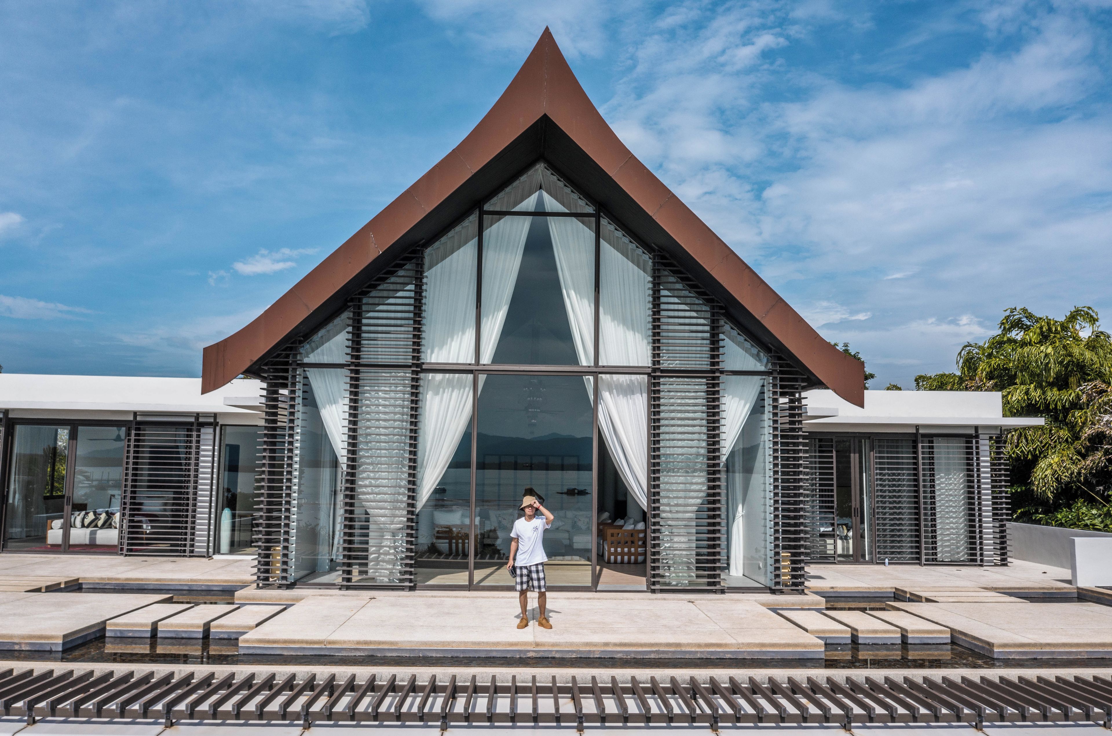 Un bâtiment moderne doté d’un toit triangulaire et de grandes fenêtres en verre.