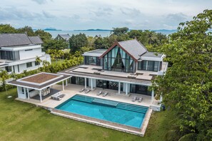 Una casa moderna con una amplia piscina, varias habitaciones y vista al mar.