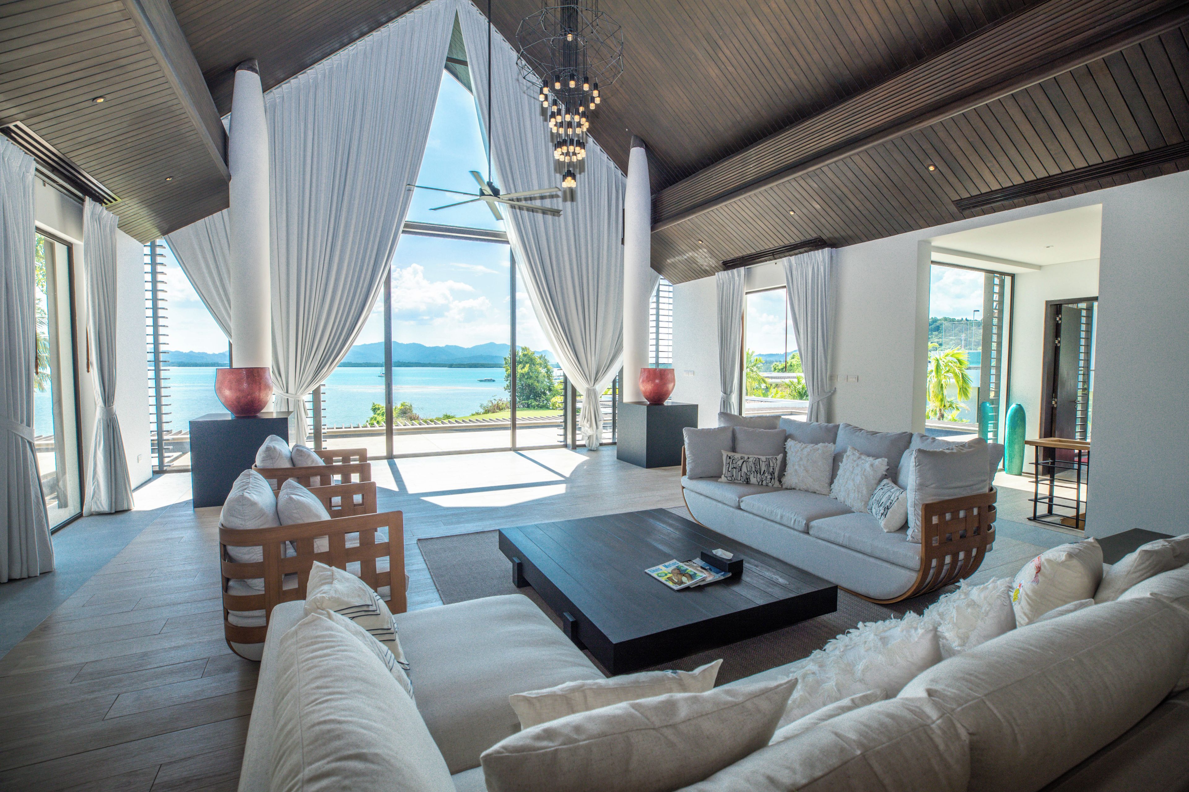 A spacious living area with a large window overlooking a body of water, a sofa set, and a coffee table.