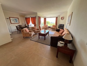 A living room with a sofa, armchairs, a coffee table, a TV, and a dining area with chairs and a table. - Spacious 2 bed 2 bath apartment in beautiful Windmill Hill complex with Air Con. (Albufeira)