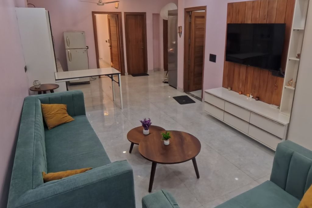 Un salon avec un canapé, une table basse et un téléviseur fixé au mur.