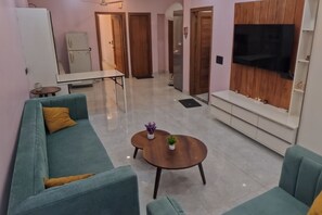 A living room with a sofa, a coffee table, and a television mounted on the wall.
