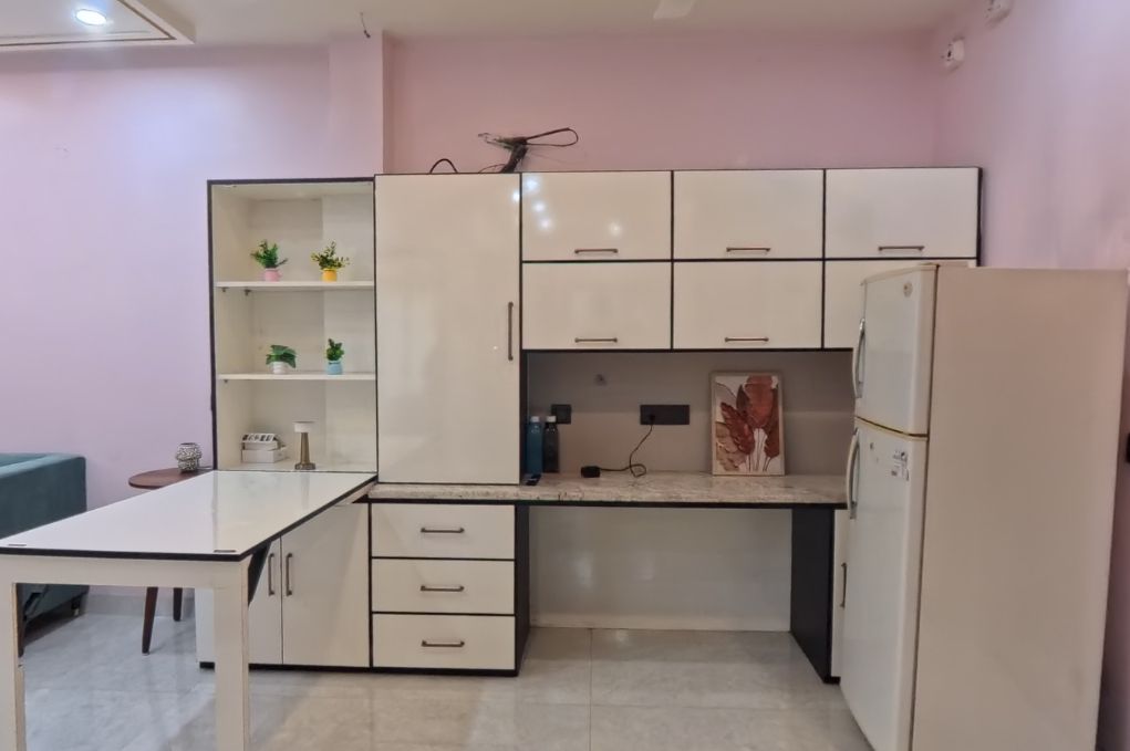 Eine kleine Küche mit weißen Schränken, einer Arbeitsfläche und einem Kühlschrank.