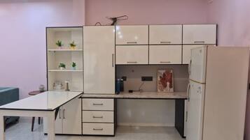 Eine kleine Küche mit weißen Schränken, einer Arbeitsfläche und einem Kühlschrank.