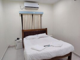Ein Hotelzimmer mit einem Bett, einem Nachttisch und einer Klimaanlage.