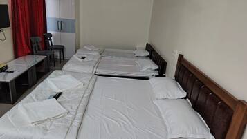 A hotel room with two beds, a desk, a chair, a wardrobe, and a red curtain.