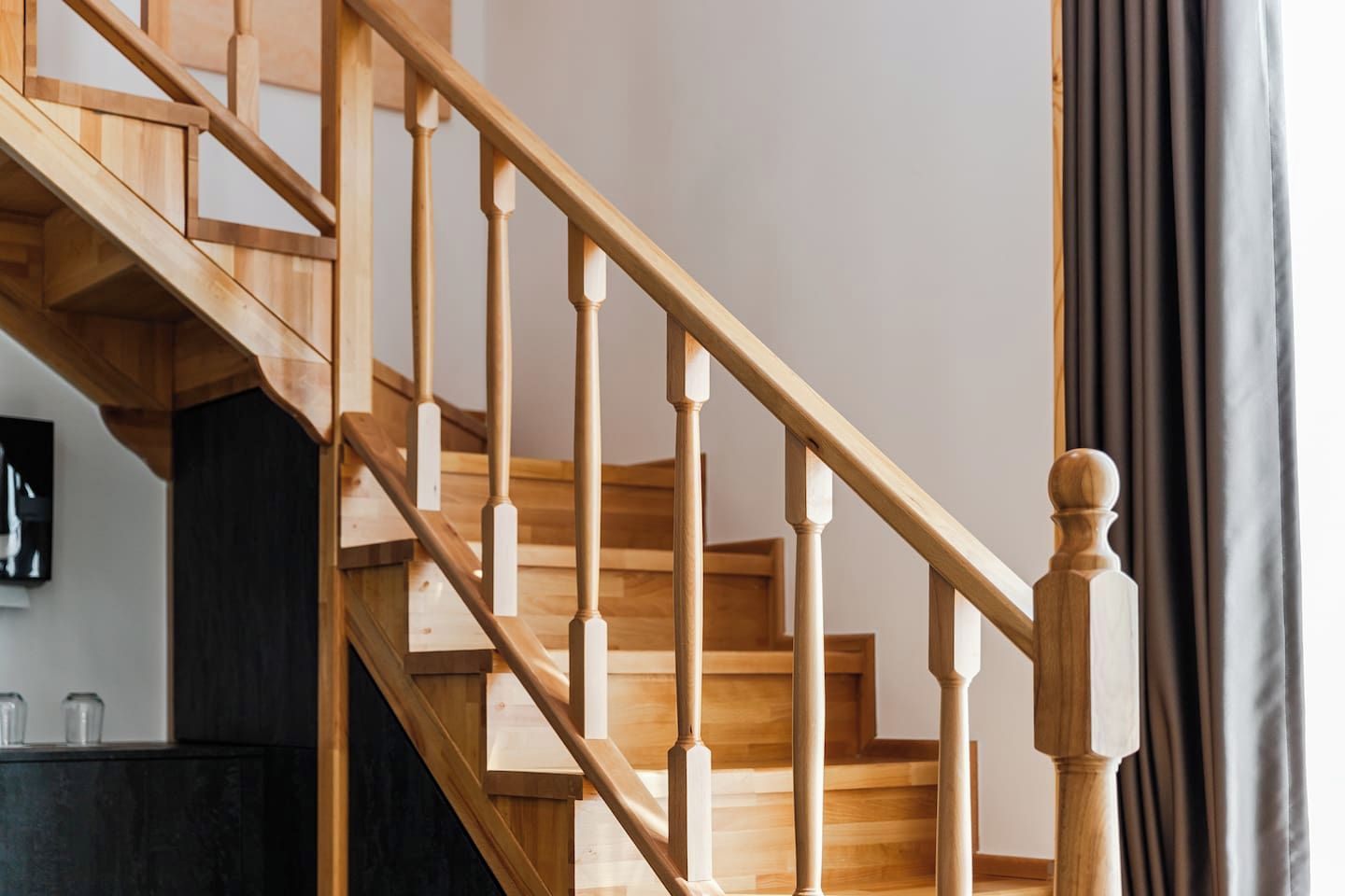 A wooden staircase with a handrail and a dark wall behind it.