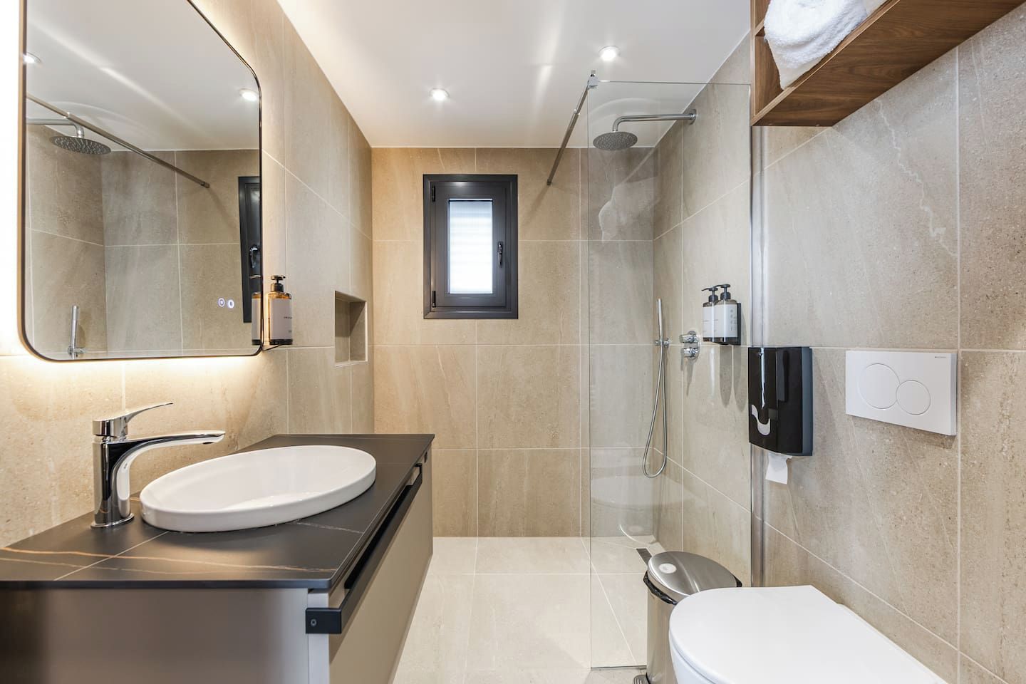 A modern bathroom with a sink, mirror, shower, and toilet.