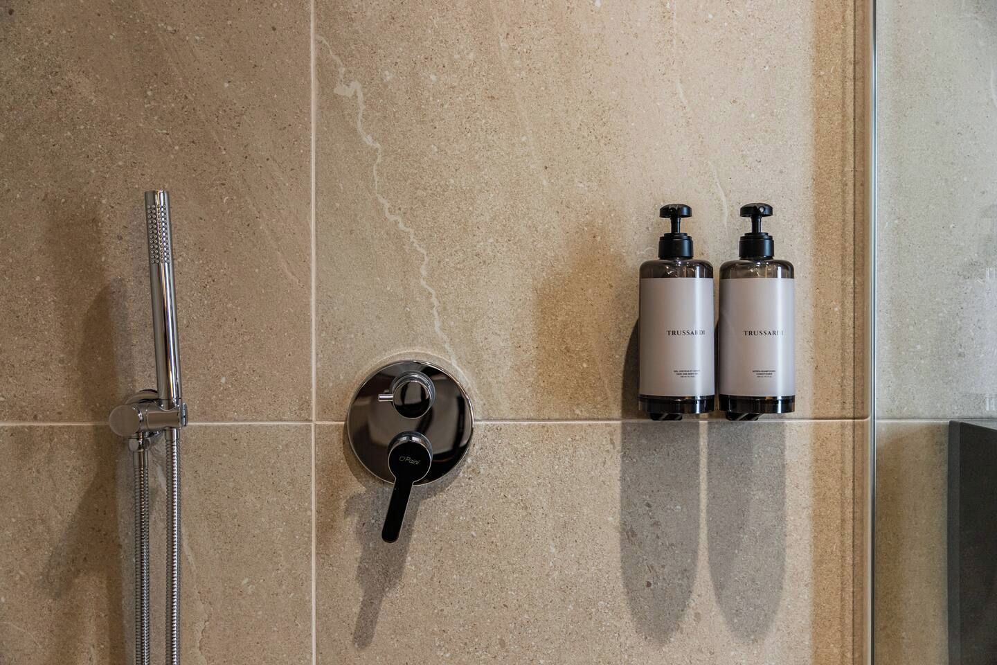 Ein Badezimmer mit Dusche, einer Bedienkonsole und zwei Flaschen Trussardi Pflegeprodukten.