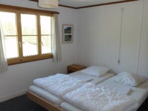 A simple room with a bed, a nightstand, a window, and a picture on the wall. - Buebebärg Ferienhaus, Dusche und Bad, WC, 2 Schlafräume 3.5-Zimmerwohnung by Interhome (Adelboden)