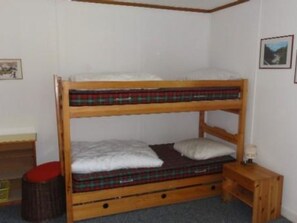 A bunk bed with a plaid mattress cover, a small wooden stool, and a framed picture on the wall. - Buebebärg Ferienhaus, Dusche und Bad, WC, 2 Schlafräume 3.5-Zimmerwohnung by Interhome (Adelboden)