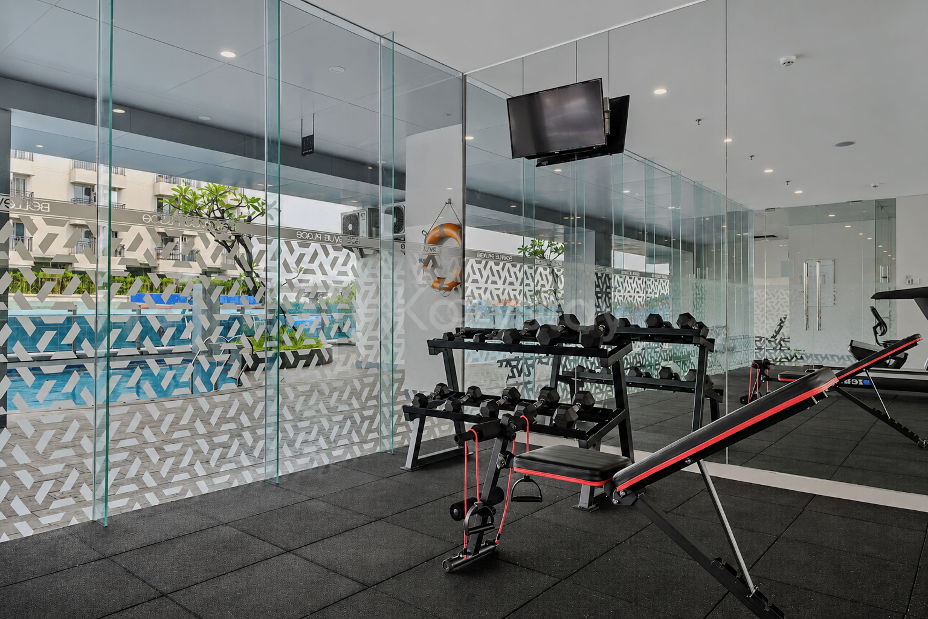 A modern gym with glass walls, exercise equipment, and a television.