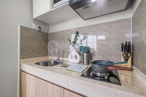 A kitchen with a stainless steel sink, a gas stove, and various utensils. - Galini by Kozystay - Tebet (South Jakarta)