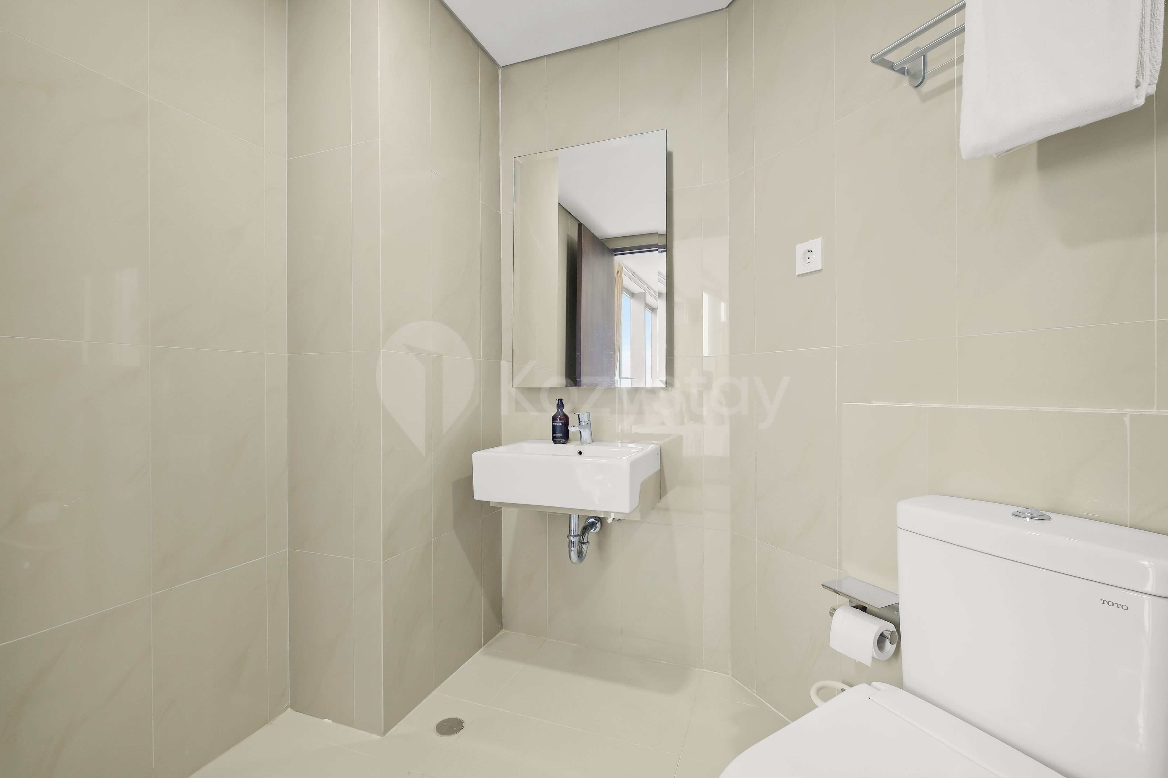 A bathroom with a white sink, mirror, toilet, and a towel rack.