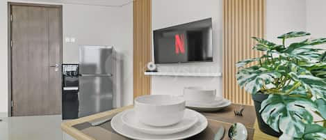 Una cocina moderna con refrigerador incorporado, microondas y televisor de pantalla plana montado en la pared.