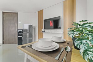 Een moderne keuken met een inbouwkoelkast, een magnetron en een flatscreen televisie aan de wand.