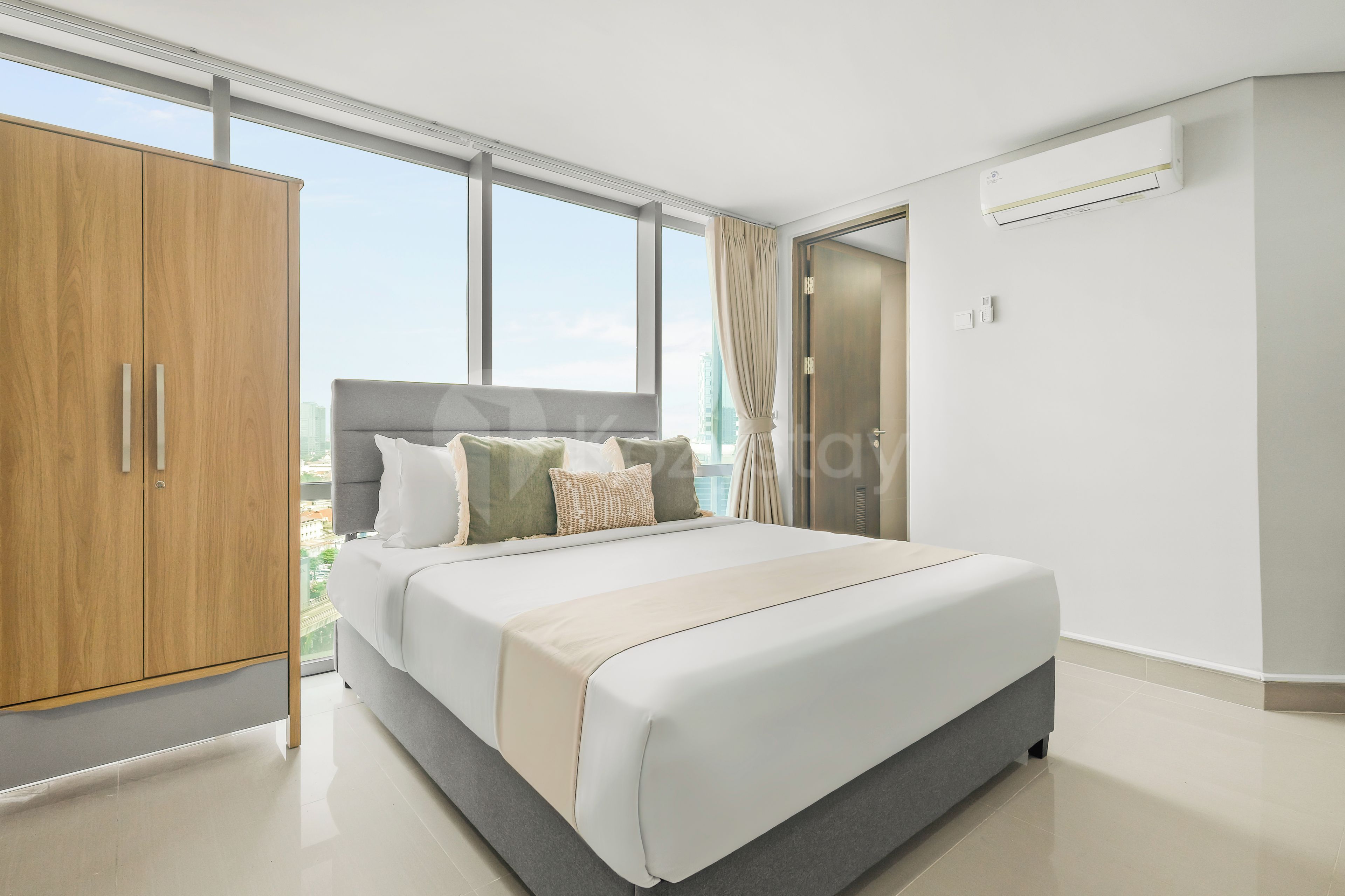A modern bedroom with a large bed, a wardrobe, and a view of the city.