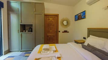 Una habitación de hotel con una cama, un armario, un espejo y un cuadro en la pared.