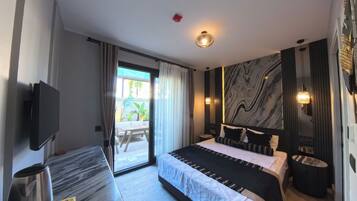 Una habitación de hotel moderna con una cama grande, un televisor de pantalla plana, una mesita de noche de mármol y una puerta corredera de vidrio al exterior.