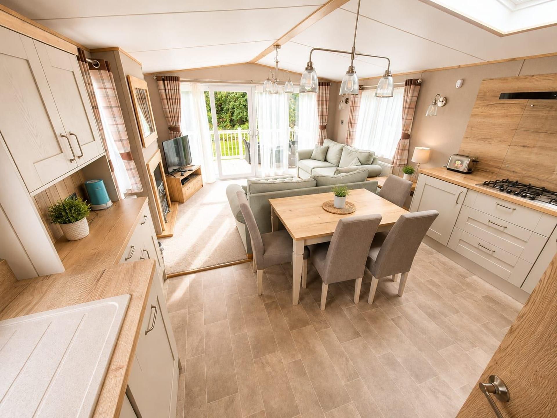 A compact kitchen with a dining area, a sofa, and a TV.