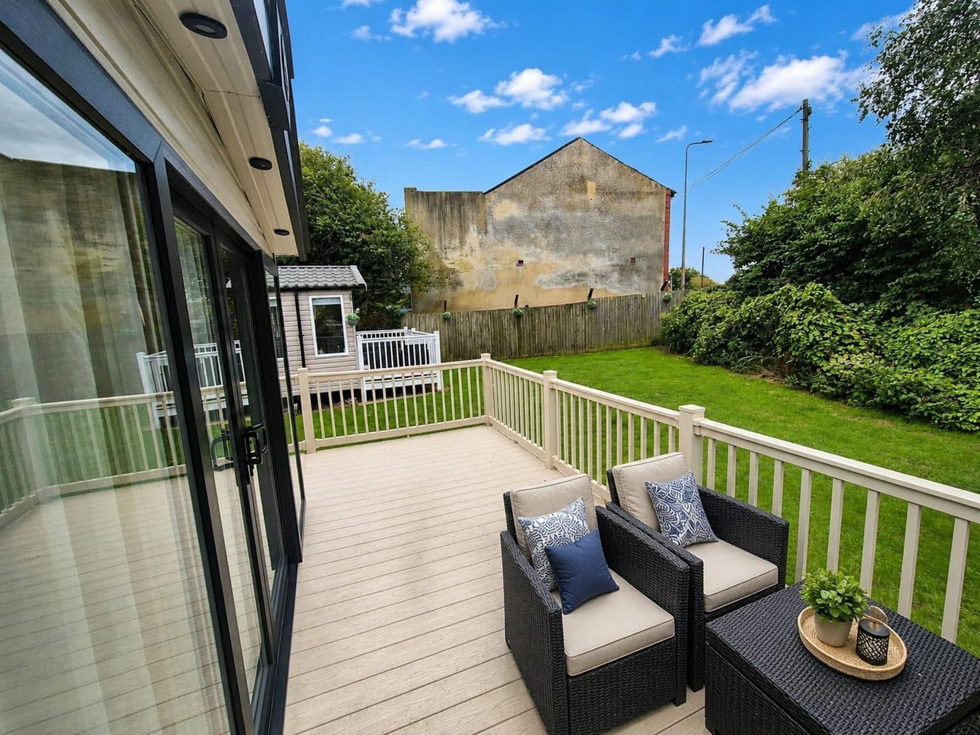 A deck with outdoor furniture and a view of a building with a textured wall.