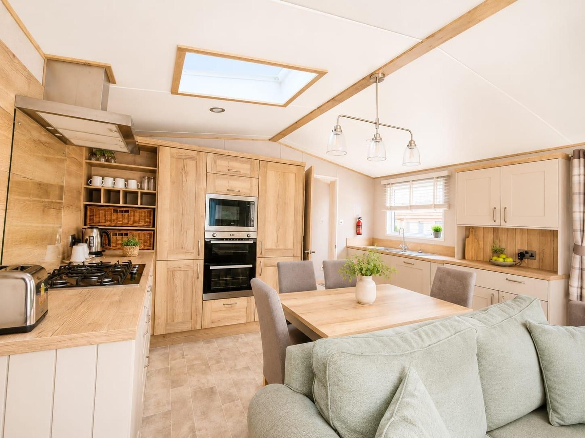A compact kitchen with a dining area, featuring wooden cabinets, a microwave, a stove, and a dining table with chairs.