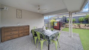 An outdoor patio area with a table and chairs, a wooden cabinet, and a ceiling fan. - Entire 4BR Logan Hidden Gem w/ Pool Near Tamborine (Yarrabilba)