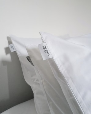 Pillows with tags labeled 'HAKANTO HOUSE' on a white wall. - Hakanto House (Antananarivo)