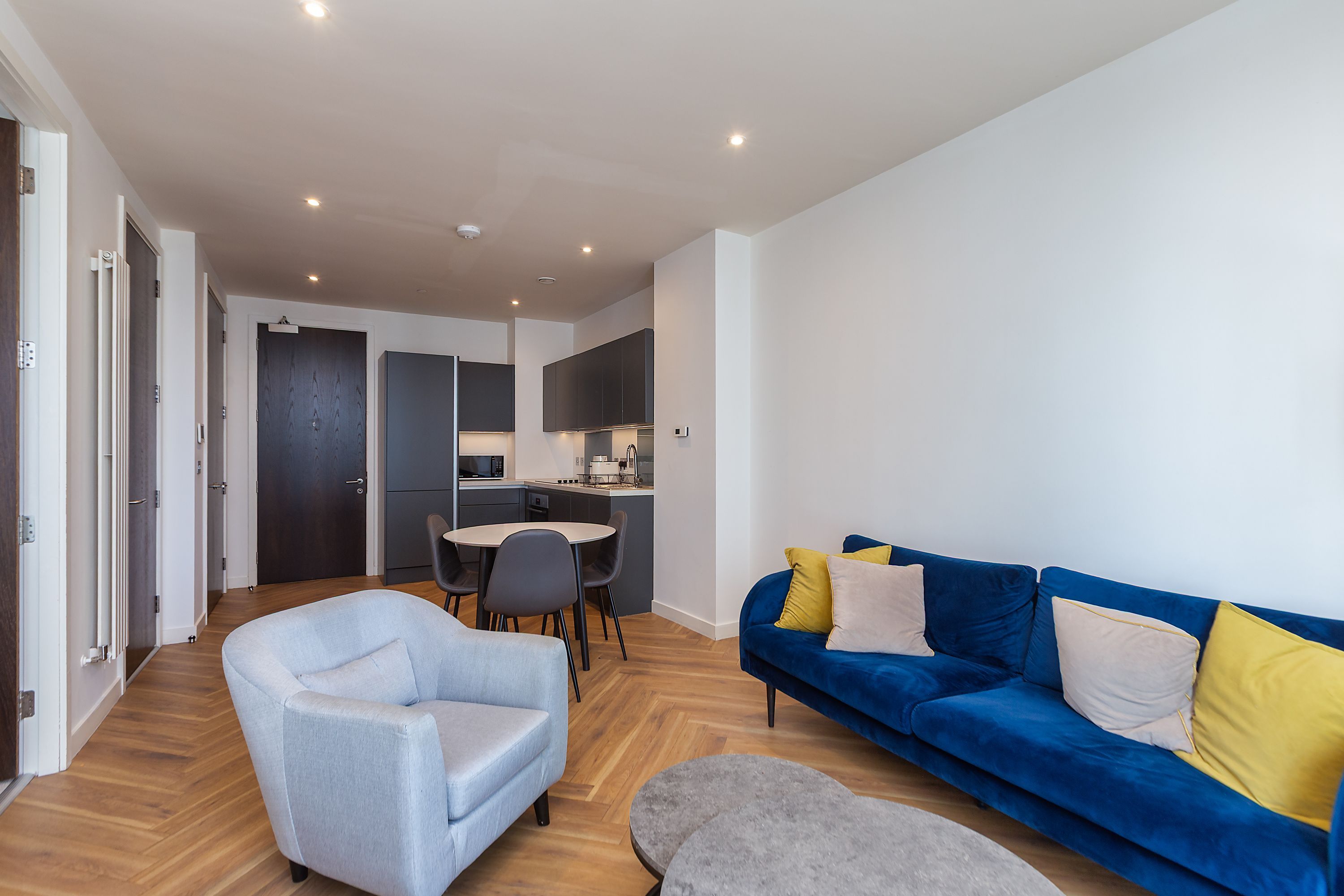Un salon moderne avec un canapé bleu, un fauteuil gris et une petite table ronde.