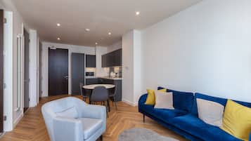 A modern living room with a blue sofa, a grey armchair, and a small round table.