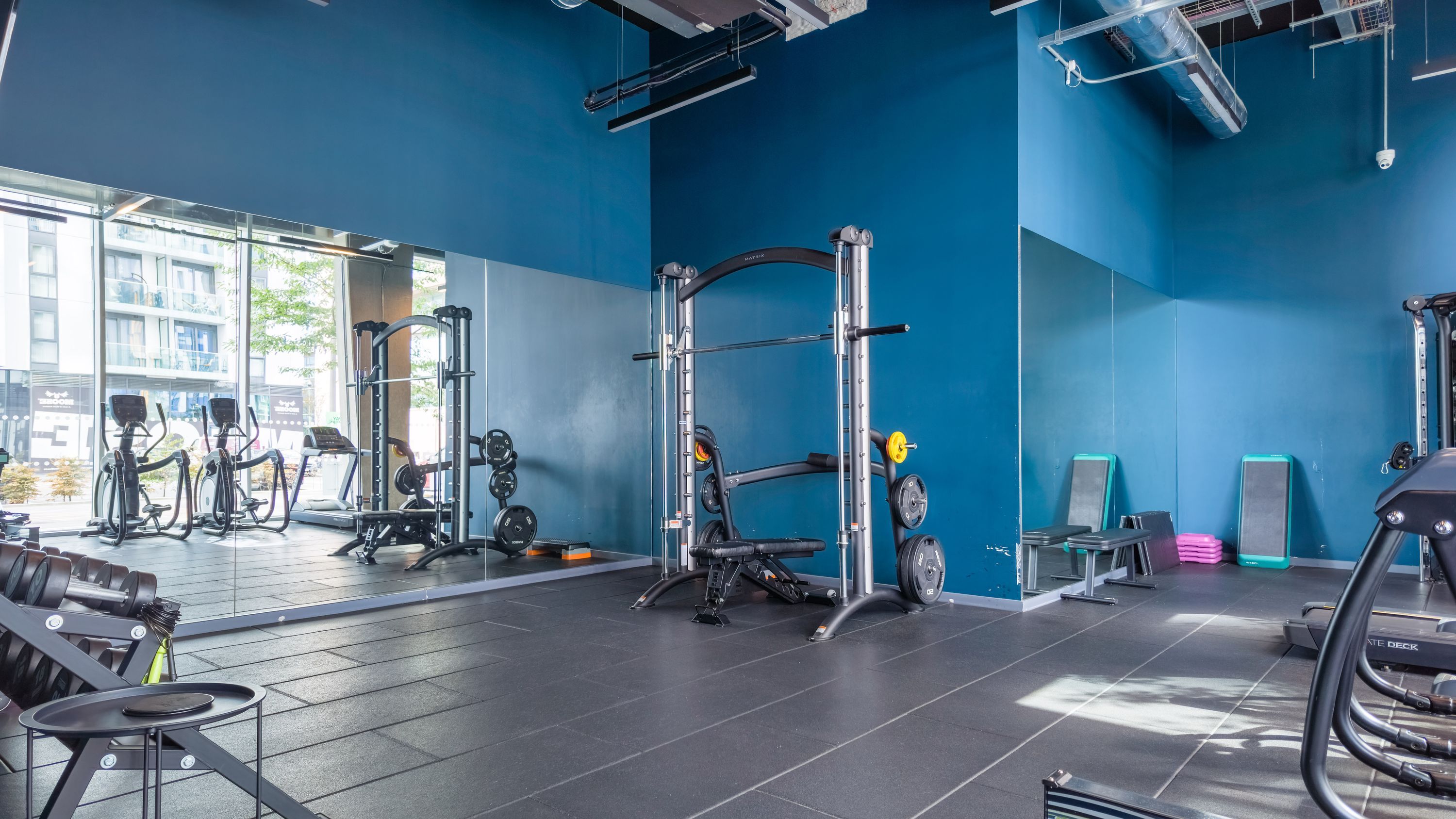 A gym with exercise equipment, a weight rack, and a view of the outside.