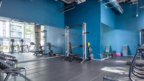 Une salle de sport équipée de matériel d’exercice, de supports pour les poids et offrant une vue sur l’extérieur.