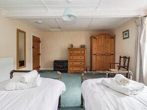 A room with two beds, a wooden wardrobe, a chair, a radiator, and a ceiling light fixture. - South View (Richmond)