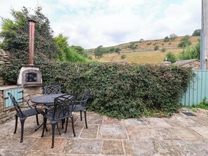 An outdoor patio with a stone table and chairs, a brick oven, and a view of rolling hills. - South View (Richmond)