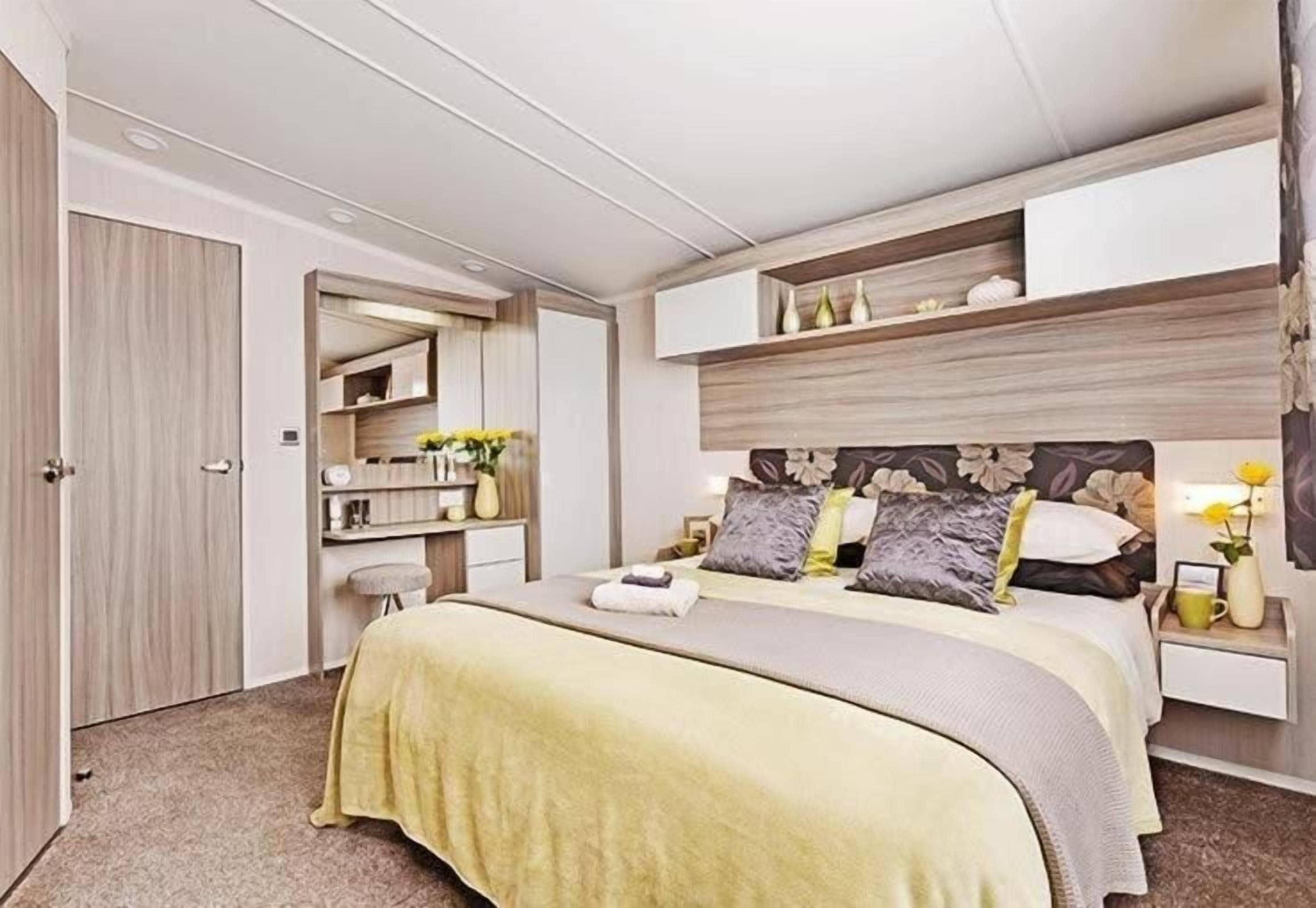 A bedroom with a bed, bedside tables, a mirror, and a wardrobe.